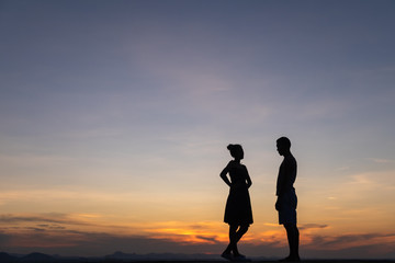 Silhouettes of happy young couple against the sunset sky.