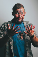 An emotional bearded man looks down at his bloodied hands and screams in fear. Concept of murder or incident,