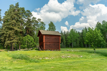 Old timbered two story barn on a green summer field in Sweden