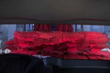 Red brush washing car in carwash. Inside view