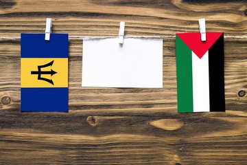 Hanging flags of Barbados and Palestine attached to rope with clothes pins with copy space on white...