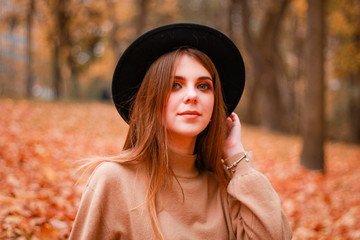 Autumn girl in the park. Sweater, hat and leather skirt. Stylish image. Atmosphere. Makeup