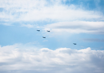 Four fighter planes flying in formation in some maneuvers on October 12, is Spain with a cloudy blue sky background
