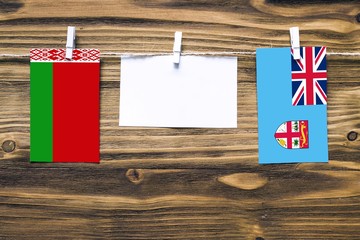 Hanging flags of Belarus and Fiji attached to rope with clothes pins with copy space on white note...