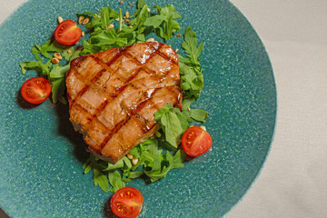 Grilled beef steak with fresh arugula and baby tomato served in a restaurant