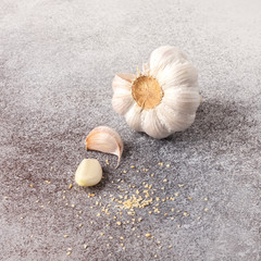 fresh whole garlic, garlic cloves and garlic granules on stone background