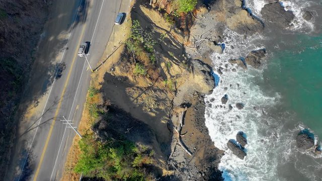 Aerial: Car Driving on Cliff Road Past Scenic Ocean Lookout With Colorful Jaco Welcome Sign
