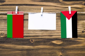 Hanging flags of Belarus and Palestine attached to rope with clothes pins with copy space on white...