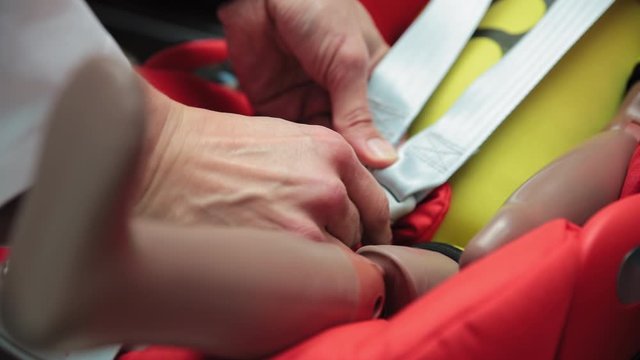 Close up of a person buckling up crash test dummy before testing
