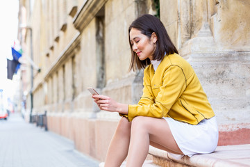 Smiling asian woman working on mobile smart phone while sitting on the floor Asian woman talking on mobile cellphone texting and surfing the net