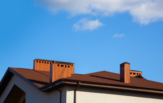 Chimneys on the roof of the house, against the blue sky