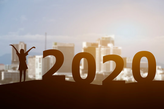 Concept Happy new year 2020 Silhouette image of Young fit woman hands up stretching with city background.