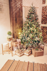 Fototapeta na wymiar New year winter home interior. Christmas tree holiday decorations, firewood, eco gift boxes made with craft paper. White stylish cozy scandinavian style living room. Festive home night muffled light
