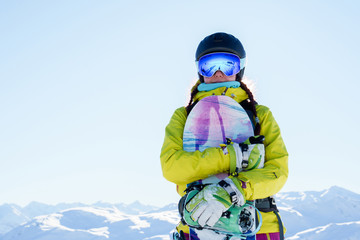 Fototapeta na wymiar Image of sportswoman in helmet and goggles with snowboard at ski resort .