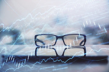 Financial graph hologram with glasses on the table background. Concept of business. Double exposure.