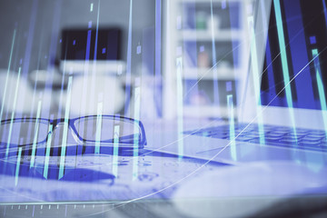 Financial chart hologram with glasses on the table background. Concept of business. Double exposure.