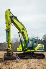 Modern excavator performs excavation work on the farm field.