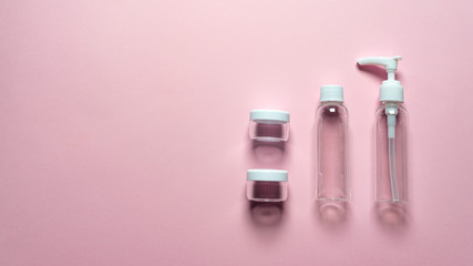 Travel set of bottles and jars on a pink background