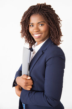 Happy successful professional holding folder with documents and reports, looking at camera. Young African American business woman posing isolated over white background. Business portrait concept