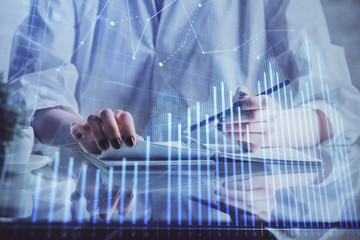 Financial forex graph drawn over hands taking notes background. Concept of research. Double exposure