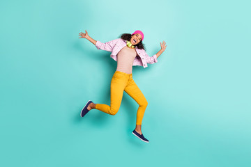 Photo of casual positive cute nice pretty charming girlfriend wearing pants trousers striped t-shirt pink jacket yellow cap headwear running jumping isolated vivid teal color background