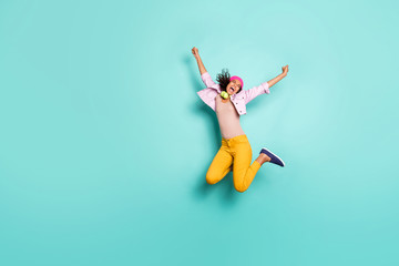 Fototapeta premium Full length body size photo of overjoyed ecstatic rejoicing girl causal jumping screaming in striped t-shirt pink jacket cap headwear yellow trousers isolated vivid color background turquoise