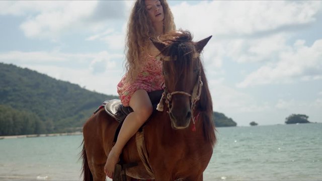 Free confident woman riding horse on seaside