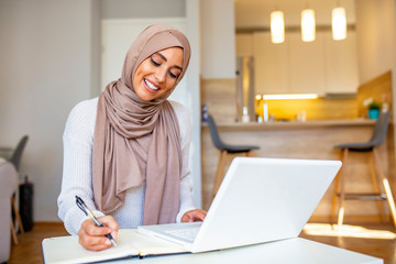Attractive female Arabic working on laptop computer and paperworks on desk. Arabian Businesswoman...