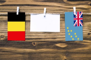 Hanging flags of Belgium and Tuvalu attached to rope with clothes pins with copy space on white...