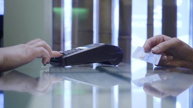 Female hand attache card to the terminal for payment.