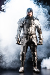 Fototapeta premium handsome knight in armor looking at camera on black background