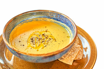Pumpkin cream soup in a blue deep plate, isolate on a white background