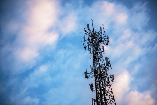 Wireless communication tower with blue sky and white clouds as background