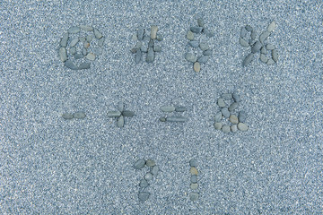symbols of stone font on gray sand background. different symbols lined with stones on blue sand background.