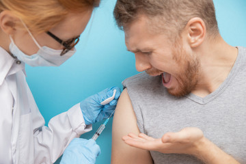 Obraz premium Fear of syringe injections and vaccinations doctor appointment. Man is afraid of nurse