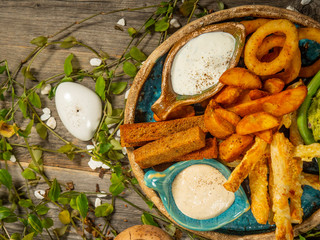 Plate with snacks for beer. French fries, cheese sticks, onion rings and white sauce