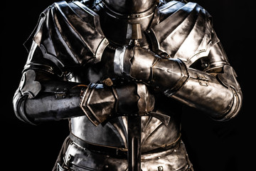 cropped view of knight in armor holding sword isolated on black - obrazy, fototapety, plakaty