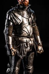 Fototapeta na wymiar cropped view of knight in armor isolated on black