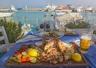 Fotobehang Een zomerdiner. Niet-geïdentificeerde mensen die een traditioneel heerlijk mediterraan gerecht buitenrestaurant eten in Cyprus, Ayia-napa. Lekkere en authentieke Cypriotische keuken © natalia_maroz