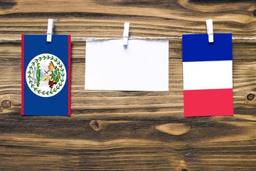Hanging flags of Belize and France attached to rope with clothes pins with copy space on white note...