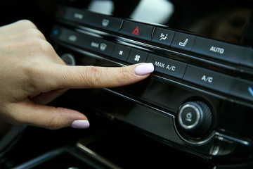 driver's finger presses the button for maximum air conditioning inside the car