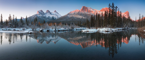 Almost nearly perfect reflection of the Three Sisters Peaks in the Bow River. Near Canmore, Alberta...