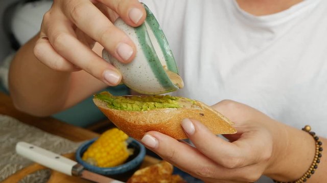Girl pours sesame sauce on a bruschetta with avocado. Breakfast time. Healthy Eating. Vegan Food. Close-up