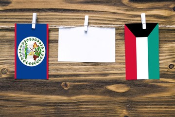 Hanging flags of Belize and Kuwait attached to rope with clothes pins with copy space on white note...