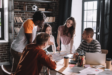 young multicultural businesspeople discussing business ideas near desk in office