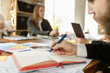 Group of young business professionals having a meeting. Diverse group of coworkers discuss new decisions, plans, strategy. Creative workplace, business, finance, teamwork. Close up of writing man.