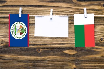 Hanging flags of Belize and Madagascar attached to rope with clothes pins with copy space on white...