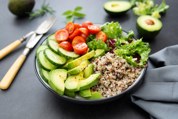 Healthy food. budha bowl with quinoa, avocado, cucumber, salad, tomatoe, olive oil. Clean eating, diet food. Dark background.