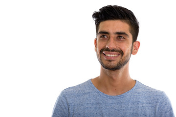 Studio shot of young happy Persian man smiling and thinking