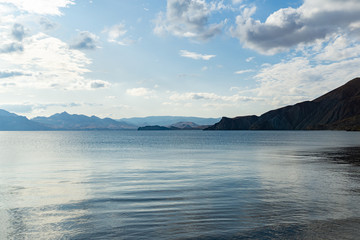 Blue sky with white clouds over the sea and mountains. Beautiful clouds and natural sky background